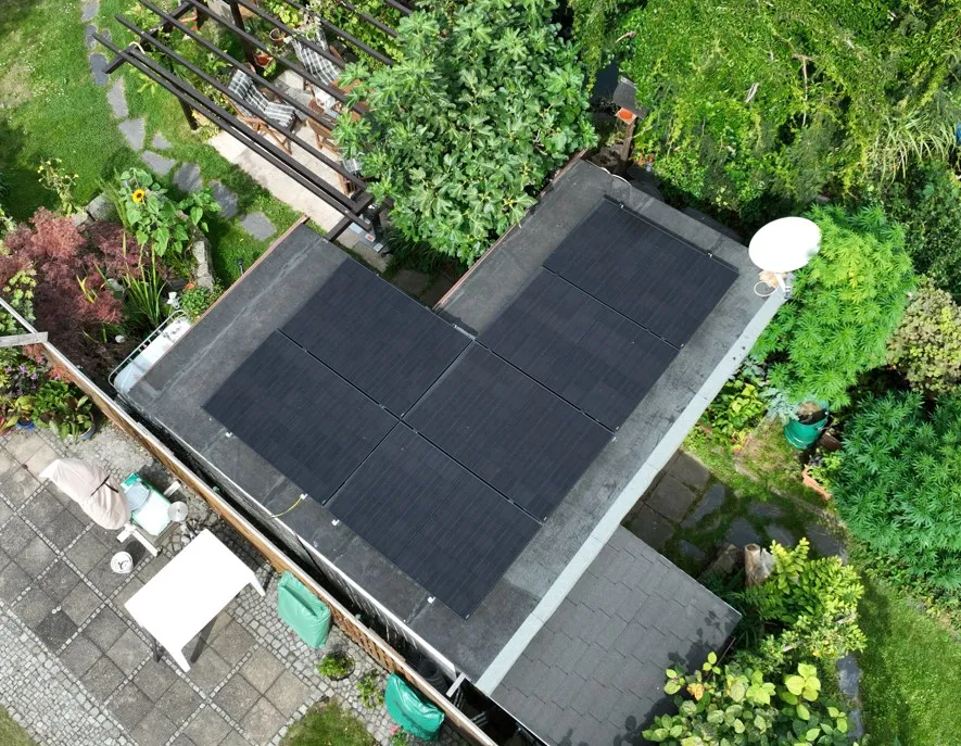 Dunkle Solarmodule auf einem flachen Gartenhausdach, umgeben von Bäumen und Beeten in Dresden-Blasewitz